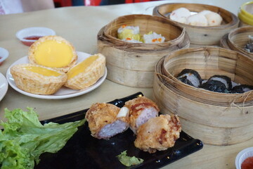 Traditional Chinese dim sum in metal bowl on wooden table. A lot of different kinds of food and...
