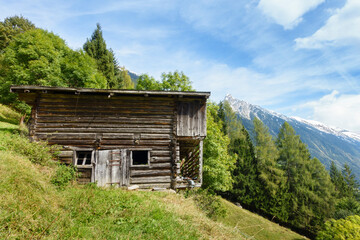 Urige alte Berghütte an einem Hang am Waldrand