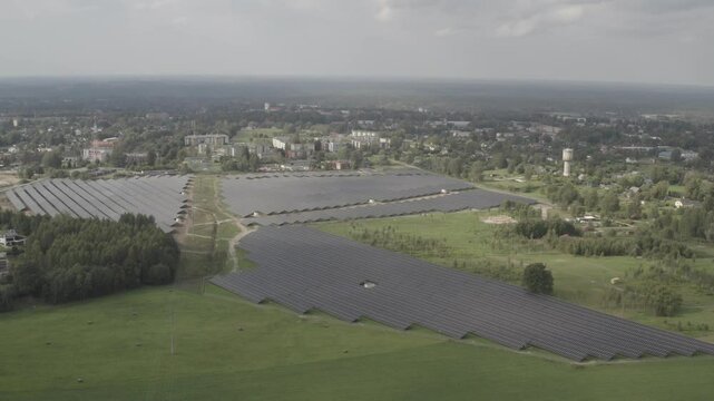 Aerial view of a solar farm in a rural landscape near a town, generating renewable energy. Captured in high-quality s-log and 4K.