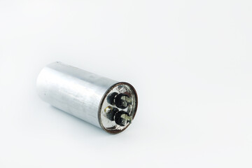 an old model of start capacitor or run capacitor is on the white table after be changed during the...