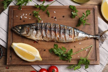 Delicious grilled mackerel, parsley, spices and lemon on wooden table, flat lay