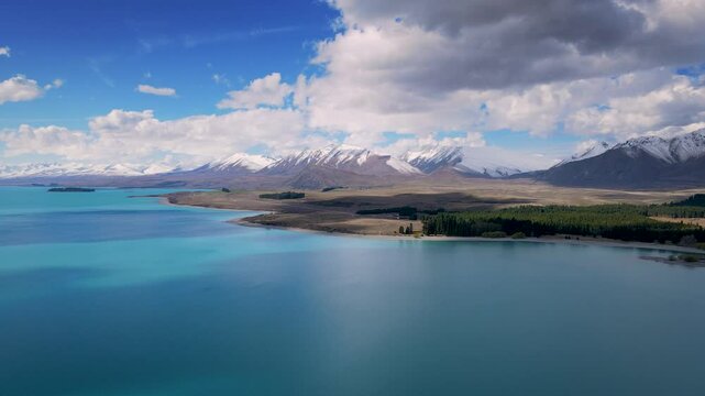 aerial view of lake tekapo new zealand, with clear sky and clouds, the lake water is bright blue