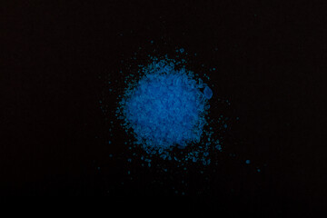 Pile of Cupric sulfate on dark surface, top view. Blue vitriol or bluestone. Bright blue crystal powder. In agriculture, copper sulfate used as antiseptic, fungicide and fertilizer