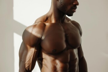 Fototapeta premium A well-toned, muscular male torso partially in focus, catching the interplay of light and shadow on his defined muscles.