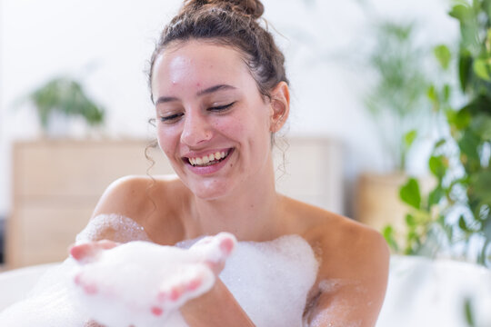 Smiling woman enjoying bubble bath, relaxing and pampering herself at home spa