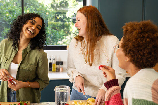 Preparing food together, diverse friends laughing and enjoying time in kitchen