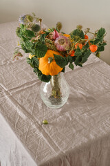 Creative vegetable bouquet in a vase on a table with a linen tablecloth. The original unusual...