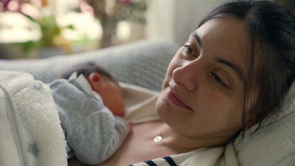 Close-up of a mother lying down with her newborn baby sleeping peacefully on her chest, capturing...