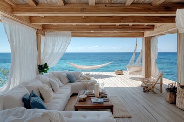 Obraz premium Spacious wooden terrace with a hammock and comfortable white seating, providing a stunning view of the blue sea under clear skies, embodying relaxation and natural beauty.