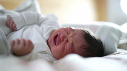Newborn baby feeling discomfort while asleep, close-up of face showing a grimace, capturing the natural expressions of early life, highlighting the vulnerability and innocence of a sleeping baby
