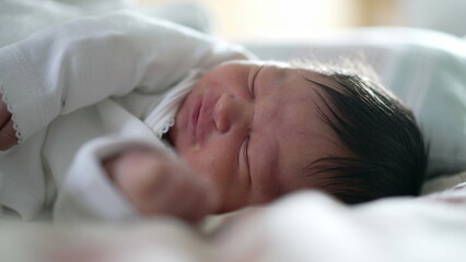 Newborn baby feeling discomfort while asleep, close-up of face showing a grimace, capturing the natural expressions of early life, highlighting the vulnerability and innocence of a sleeping baby