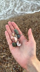 hand holding colorful rocks on beach
