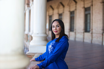 moroccan woman brunette, young and beautiful, dressed in blue abaya, typical clothes of arab woman. The woman is in the square of Spain in Seville under the arches and columns. Travel concept.