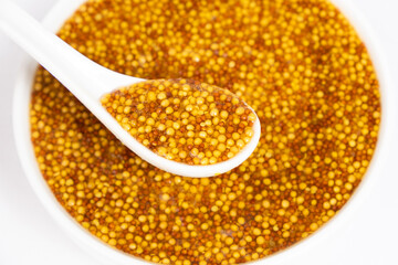 Traditional French Dijon mustard in a spoon on a white background