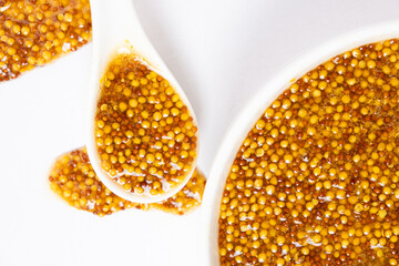 Traditional French Dijon mustard in a spoon on a white background