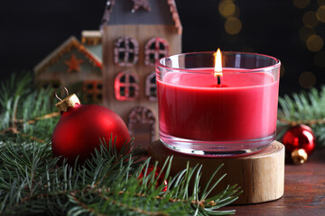 Burning candle, Christmas decor and fir tree branches on wooden table, closeup
