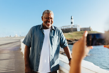 Smiling mature man posing for a photograph at Farol da Barra, Salvador