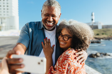 Retired happy pair taking a selfie on vacation by the ocean in Bahia
