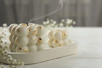 Stylish bubble candles and gypsophila flowers on white wooden table, closeup. Space for text