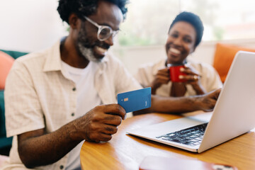 Happy couple doing online shopping together at home using a credit card