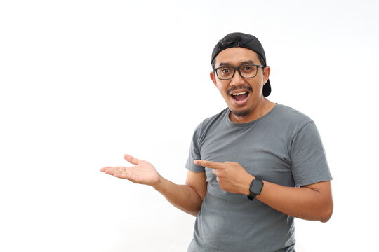 Amazed Asian man over isolated background smiling to the camera while presenting with hand and pointing with finger