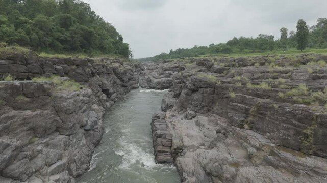 Aerial view of river flowing through the rock area. Raw footage of Beautiful nature river water and forest. D log M footage without color grad.  