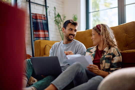 Mid adult couple talking while paying bills online at home.