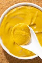 Traditional spicy mustard sauce in a spoon close-up.