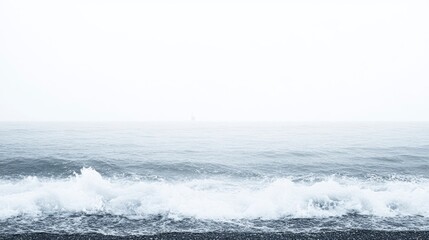 Fototapeta premium A beach covered in heavy fog, waves crashing violently, distant lighthouse barely visible