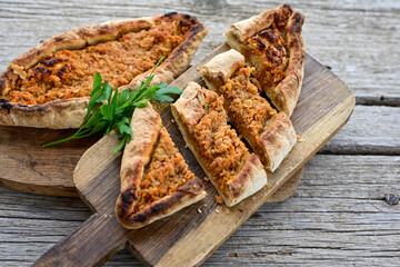  Traditional Turkish cuisine. Baked Pide dish with minced  beef, tomatoes and  herbs on  wooden background.  Turkish pizza pide