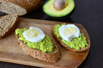 a cutting board with avocado and avocado sandwiches with egg on it