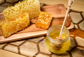 Natural organic honey in jar, honeycombs on wooden tray