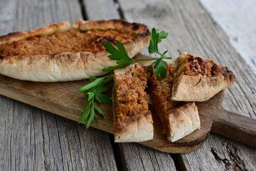  Traditional Turkish cuisine. Baked Pide dish with chicken ,  cheese and  herbs on  wooden background.  Turkish pizza pide