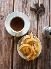 Top view of a hot chocolate breakfast with churros on wooden table