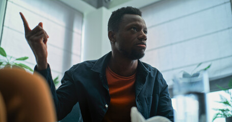 Angry African American man loses his temper, starts fight and shouts during couples therapy....