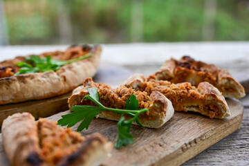  Traditional Turkish cuisine. Baked Pide dish with chicken ,  cheese and  herbs on  wooden background.  Turkish pizza pide