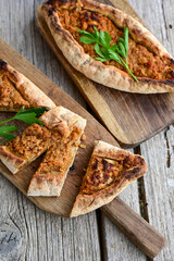  Traditional Turkish cuisine. Baked Pide dish with chicken ,  cheese and  herbs on  wooden background.  Turkish pizza pide