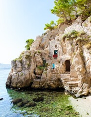 A woman ascends stone steps leading from tranquil shoreline, surrounded by vibrant greenery and...
