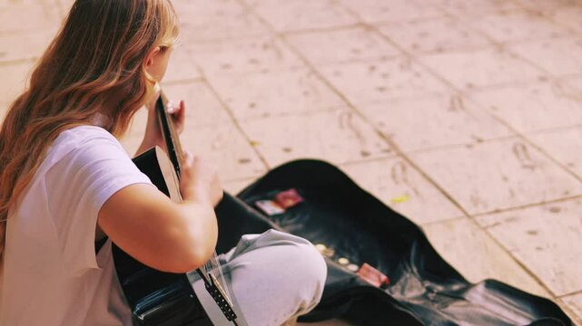 Teenager Girl Hipster Street Artist Play Guitar on Pavement, Sharing Girl Music and Talent with Passersby in Vibrant Urban Setting. Street Musician