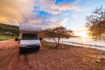 Coastal sunset with recreational vehicle, Motorhome parked by the seaside under a dramatic sunset sky