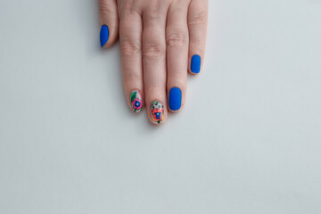 Beauty service. Female hand with blue manicured nails and flowers design. Gel varnish nail art. White background, copy space.