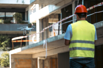 Fototapeta premium Cadastre and land registration engineers in a construction site. Topographic industry and cadastre concept photo. Male engineer operating a drone to measure the place.