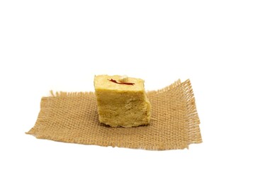 Soan Papdi or Shompapri Garnished with Cashew Nut and Saffron on Burlap Fabric Isolate on White Background with Copy Space