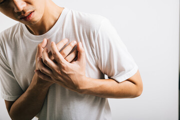 Portrait Asian young man holding his arms around his chest suffering because of a heart attack...