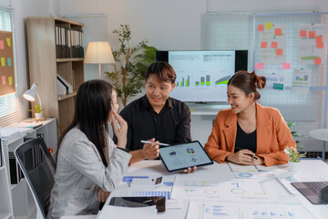 Three business professionals discussing financial data and statistics on a digital tablet during a productive meeting in a modern office