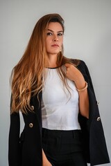 Portrait of a young woman with long hair wearing a black blazer and white top