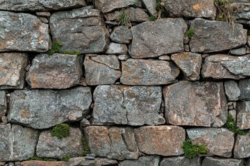 Obraz premium A Close-Up View of a Weathered Stone Wall with Patches of Greenery