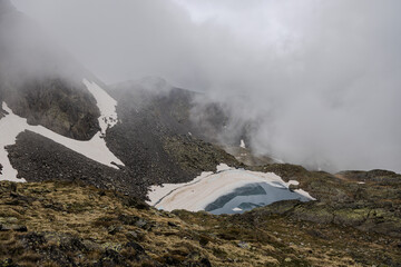 Bright blue glasier in cloudy mountains, frozen lake Montmantell in the summer in Andorra