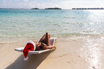 Tourist relaxing on beach wearing santa hat