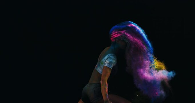 Super slow motion close up of female classical dancer or acrobatic athlete waving with hair in colorful rainbow colors holi powder splash at 1000 fps.